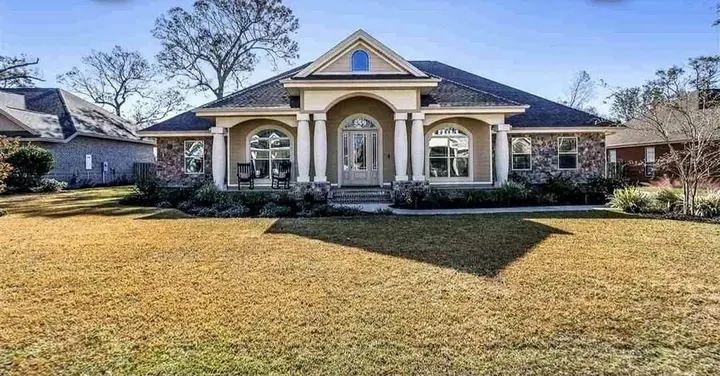 Brick home with arched windows and a columned entry on a wide lawn