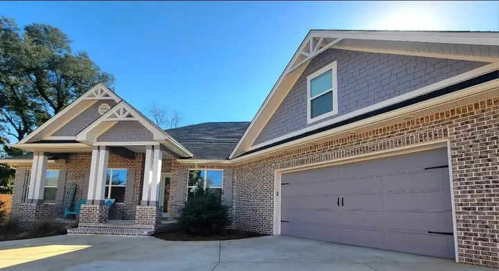 Craftsman home with brick and gray siding, a covered front porch and a carriage-style garage door