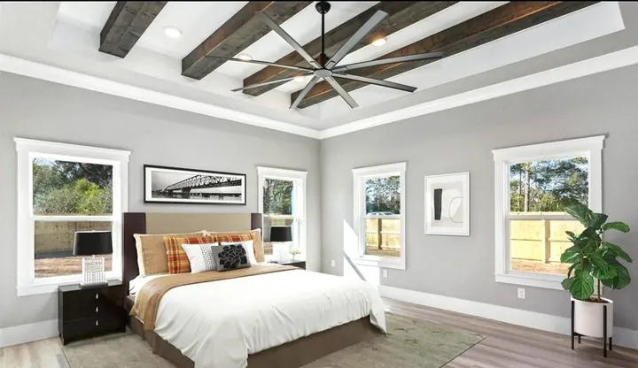 Bright primary bedroom with a tray ceiling, wood beams and a large ceiling fan