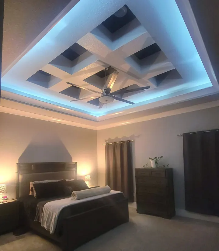 Bedroom with a coffered ceiling and blue LED cove lighting