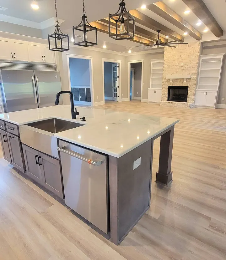 Open kitchen with a quartz island, farmhouse sink, black pendant lights and stained ceiling beams