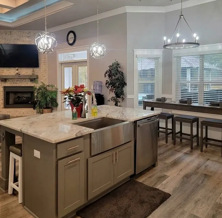 Kitchen island with a granite top, apron sink and bar seating next to a fireplace